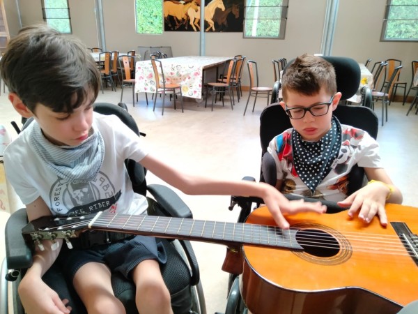 Due bambini in carrozzina suonano insieme una chitarra