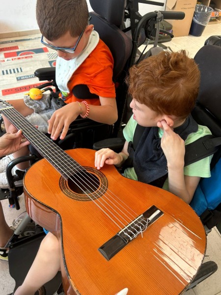 Bambini in carrozzina provano a suonare una chitarra
