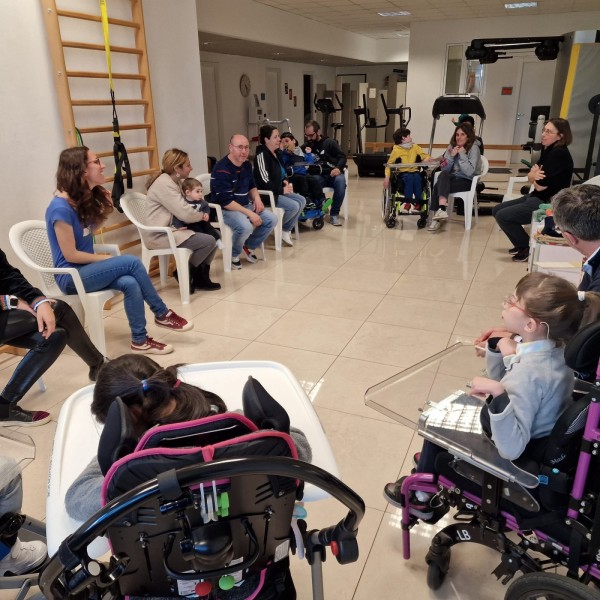 Genitori e bambini seduti in cerchio in una palestra di riabilitazione