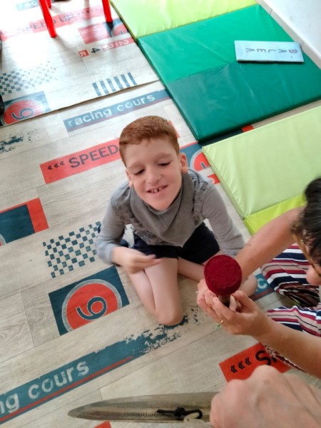 Un bambino seduto sul tappeto sorride durante un'attività con un'educatrice