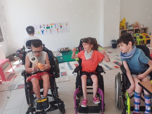Tre bambini in carrozzina sorridenti durante un incontro dell'associazione