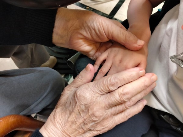 La mano di una persona anziana stringe quella di un bambino