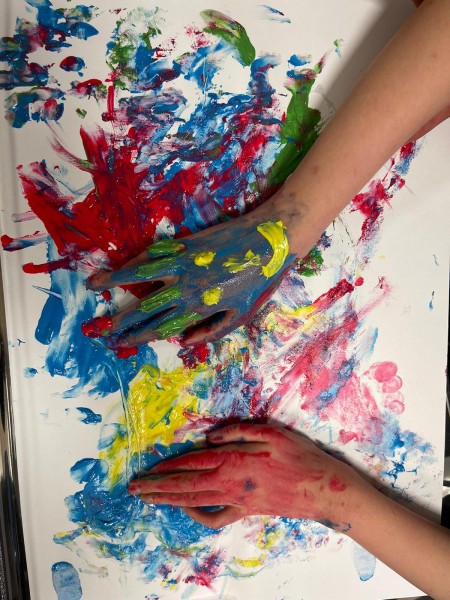Mani dipinte di colori su un foglio durante un laboratorio di pittura