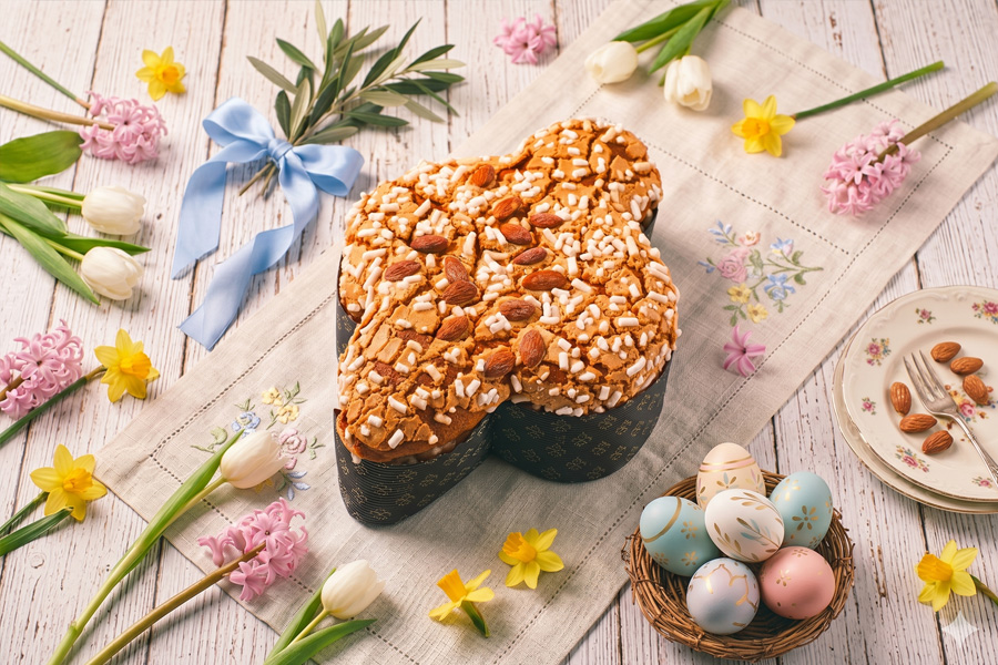 Una colomba pasquale con uova colorate e fiori di primavera